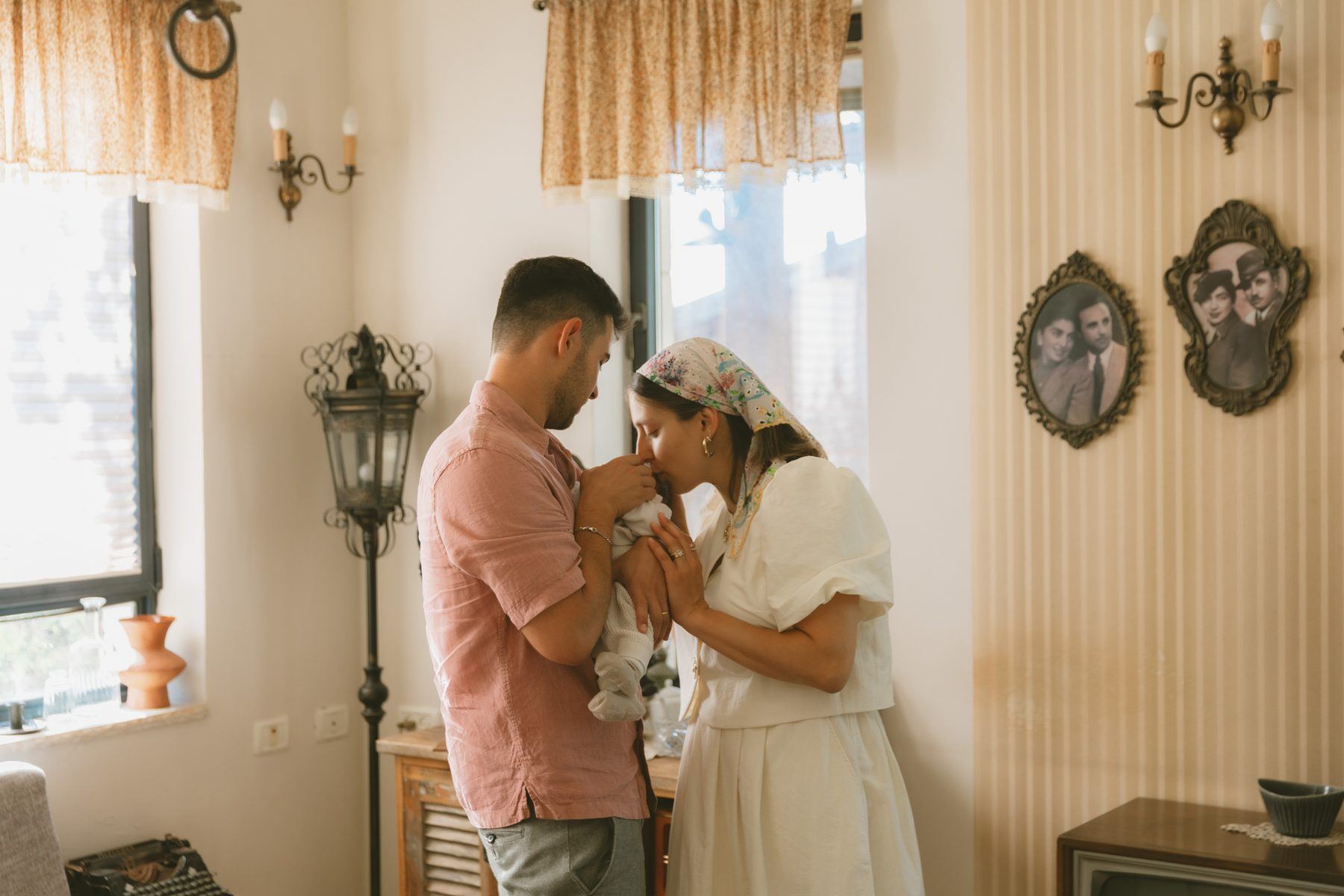 הורים מנשקים את התינוק ליד החלון